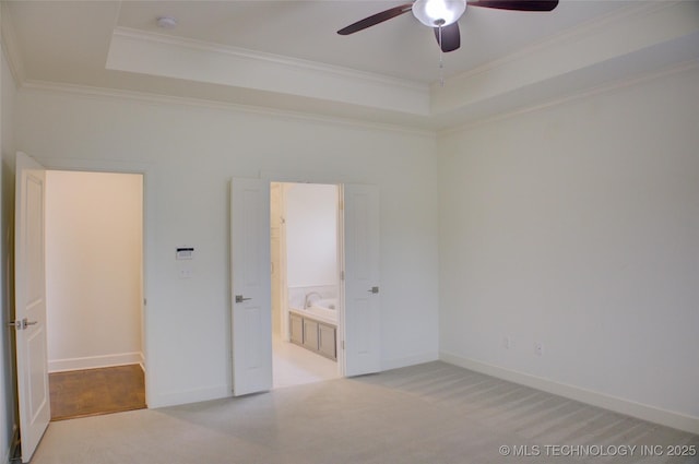 unfurnished bedroom with ensuite bathroom, ceiling fan, a tray ceiling, crown molding, and light carpet