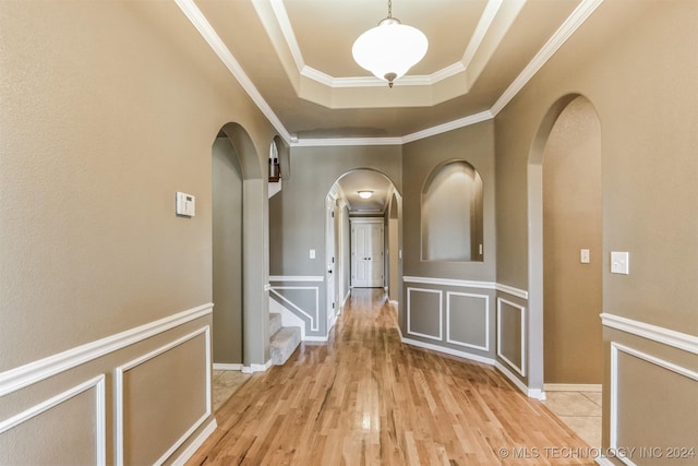 hall with a tray ceiling, light hardwood / wood-style flooring, and ornamental molding