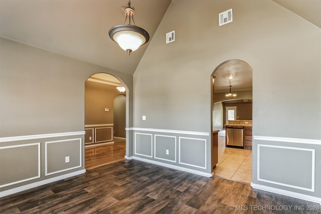 unfurnished room with high vaulted ceiling and dark wood-type flooring