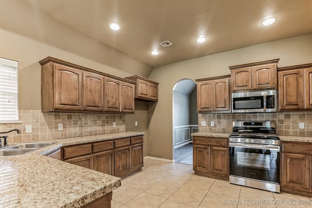 kitchen with decorative backsplash, sink, light tile patterned floors, and stainless steel appliances