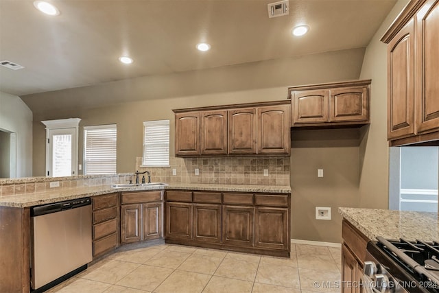 kitchen with light stone countertops, sink, stainless steel appliances, backsplash, and light tile patterned floors