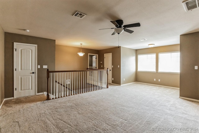 unfurnished room featuring a textured ceiling, ceiling fan, and light carpet