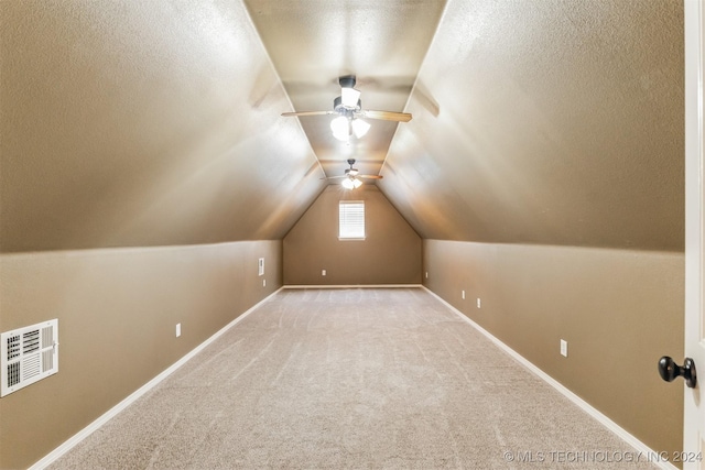 additional living space featuring a textured ceiling, ceiling fan, lofted ceiling, and light carpet