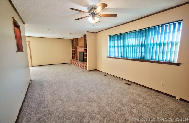 empty room featuring a wealth of natural light, ceiling fan, light carpet, and a brick fireplace