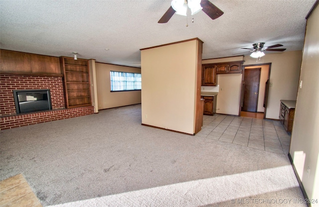 unfurnished living room with light carpet, a textured ceiling, ceiling fan, and a fireplace