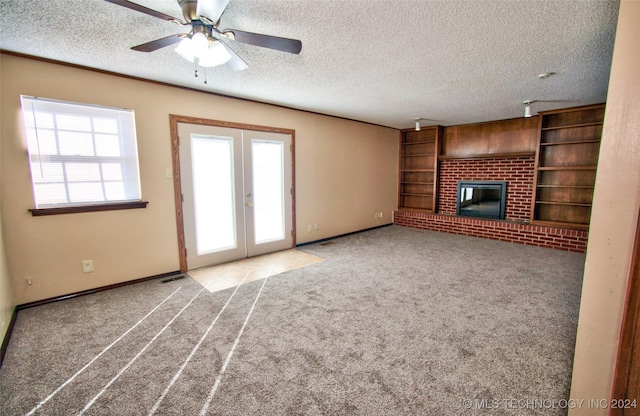 unfurnished living room with ceiling fan, french doors, a textured ceiling, light carpet, and a fireplace