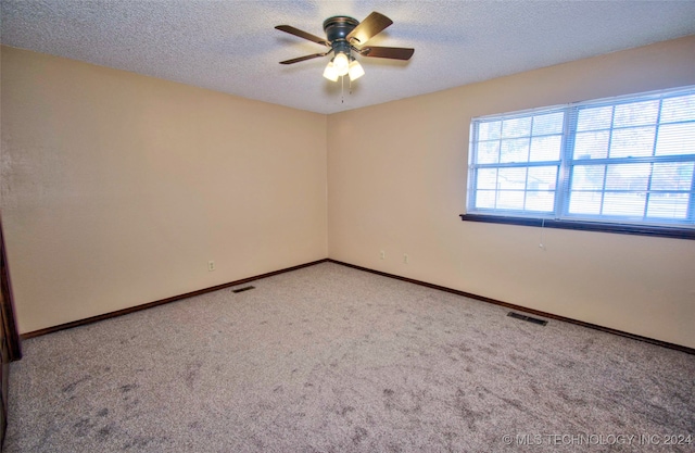 empty room featuring a textured ceiling, light colored carpet, and ceiling fan