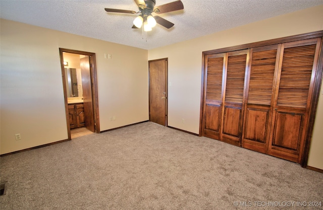 unfurnished bedroom featuring a textured ceiling, ceiling fan, ensuite bathroom, and light carpet