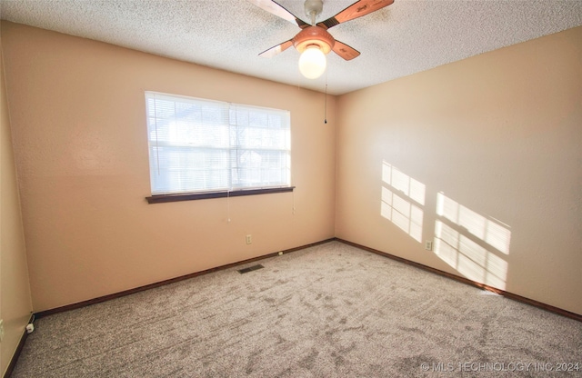 empty room with ceiling fan, carpet floors, and a textured ceiling