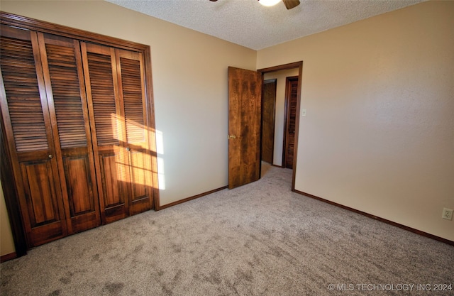 unfurnished bedroom with a textured ceiling, ceiling fan, light carpet, and a closet