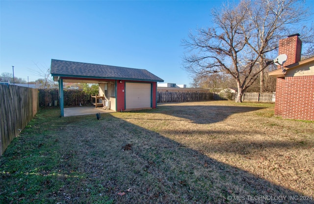 view of yard featuring an outbuilding, a patio, and a garage