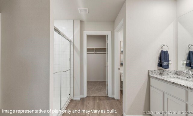 bathroom featuring vanity, toilet, a shower with door, and hardwood / wood-style floors