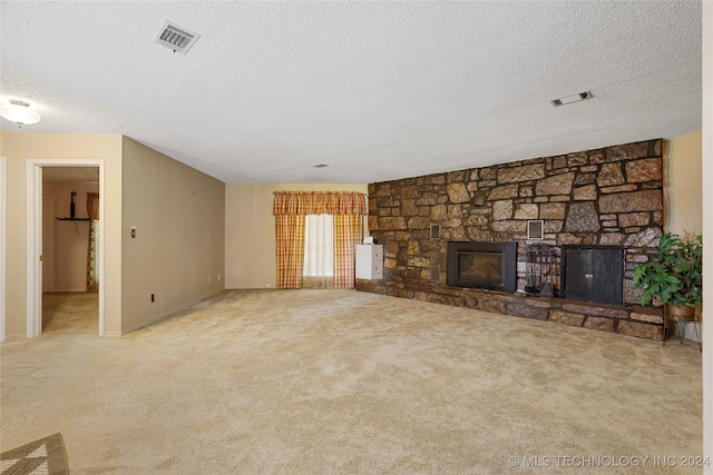 unfurnished living room featuring a textured ceiling, carpet floors, and a stone fireplace