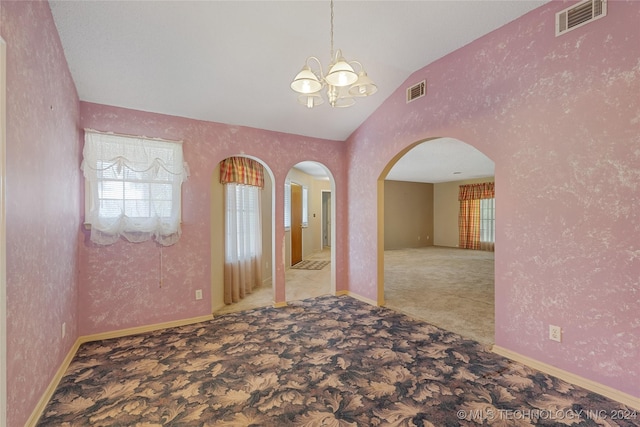 carpeted empty room featuring a notable chandelier and lofted ceiling