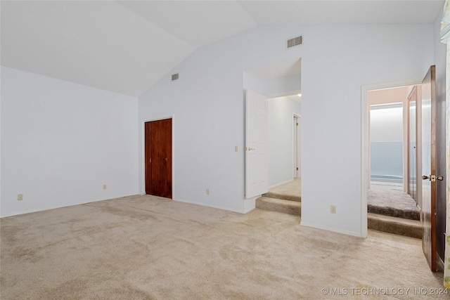 empty room featuring light colored carpet and lofted ceiling