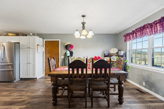 dining space featuring dark hardwood / wood-style floors, a textured ceiling, and a chandelier