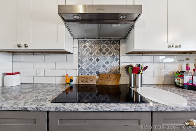 kitchen featuring black electric cooktop, light stone counters, decorative backsplash, and white cabinets