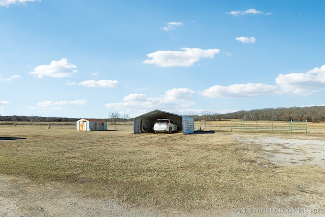 view of yard featuring a carport, a storage unit, and a rural view