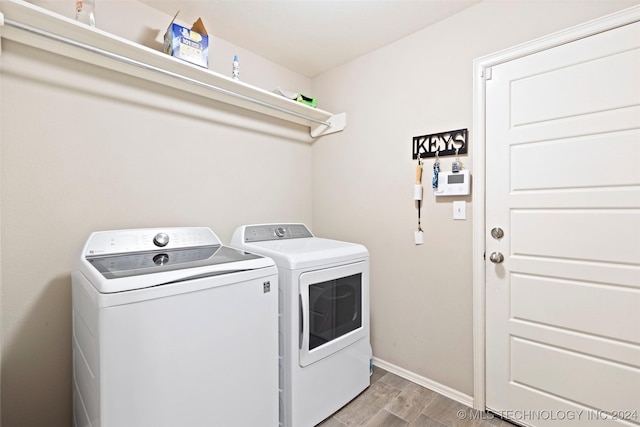 laundry area with washing machine and dryer and light hardwood / wood-style floors