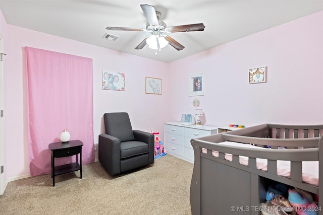 bedroom with ceiling fan, light carpet, and a nursery area