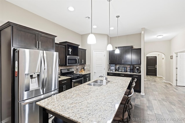 kitchen featuring sink, a kitchen breakfast bar, decorative light fixtures, a kitchen island with sink, and appliances with stainless steel finishes