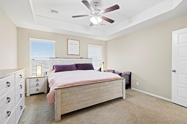 carpeted bedroom featuring ceiling fan and a tray ceiling