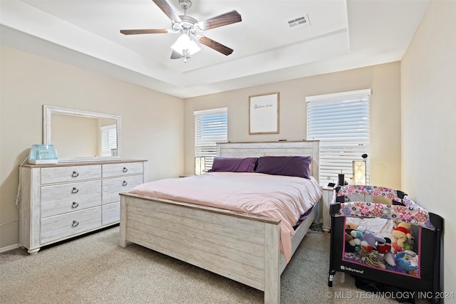 carpeted bedroom featuring a raised ceiling and ceiling fan