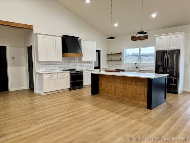 kitchen with premium range hood, double oven range, black fridge, and white cabinets