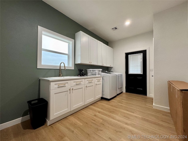 laundry area featuring sink, light hardwood / wood-style flooring, cabinets, and washer and dryer