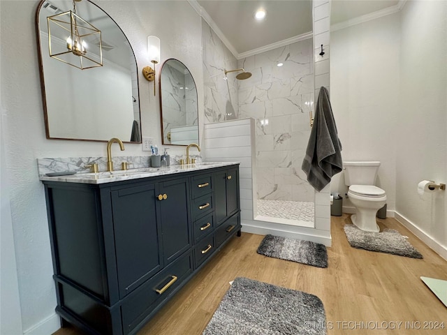 bathroom featuring a tile shower, hardwood / wood-style flooring, vanity, toilet, and crown molding