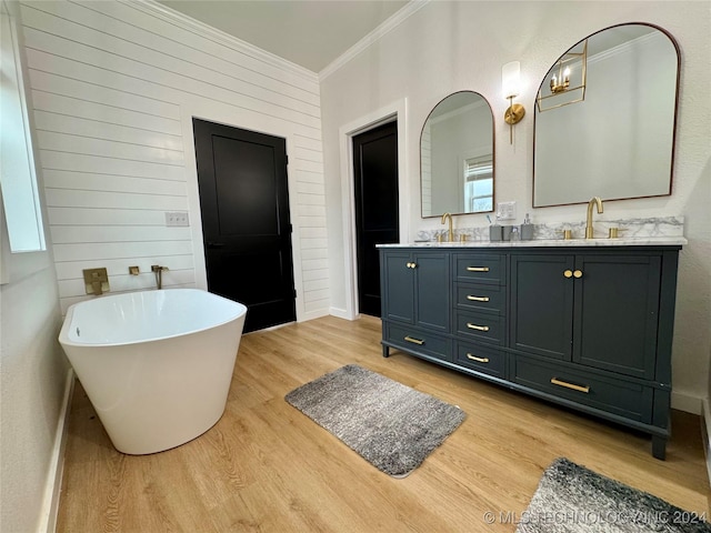 bathroom featuring wood-type flooring, vanity, a washtub, crown molding, and a healthy amount of sunlight