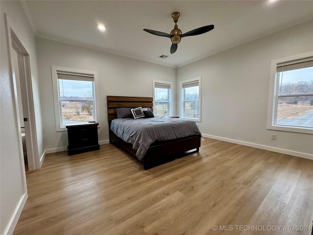 bedroom with ceiling fan, multiple windows, and light wood-type flooring