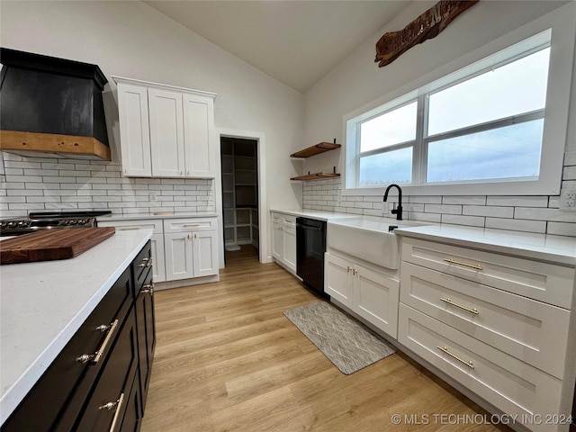 kitchen featuring sink, premium range hood, black dishwasher, white cabinets, and vaulted ceiling