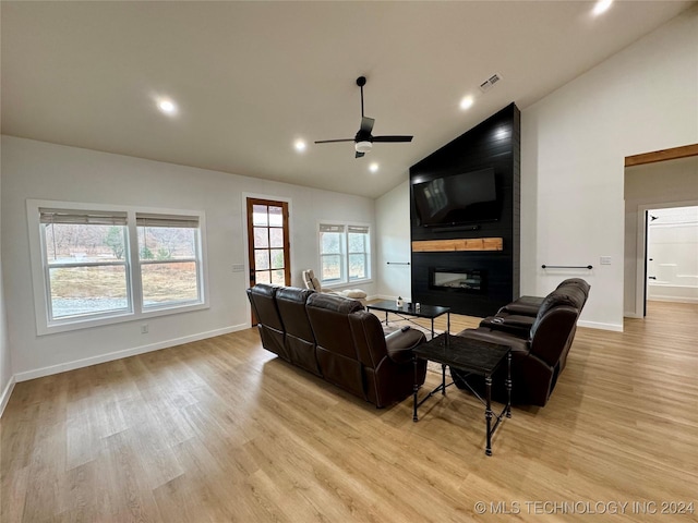 living room featuring lofted ceiling, a large fireplace, ceiling fan, and light hardwood / wood-style flooring