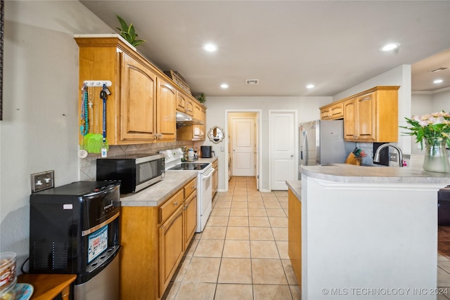 kitchen featuring kitchen peninsula, appliances with stainless steel finishes, tasteful backsplash, sink, and light tile patterned flooring