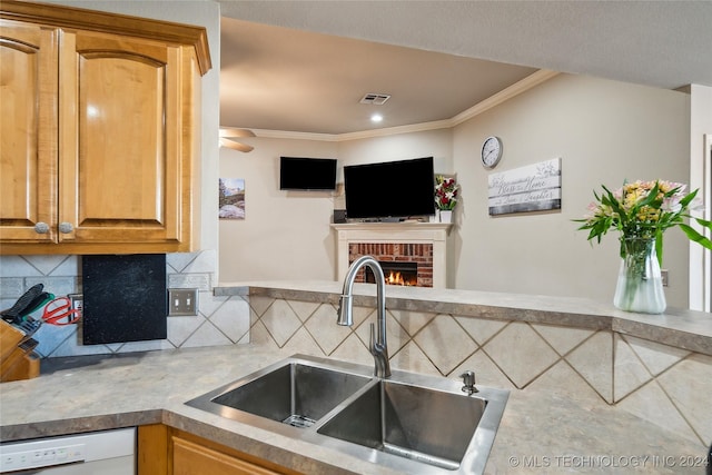 kitchen featuring decorative backsplash, a brick fireplace, ornamental molding, sink, and dishwasher