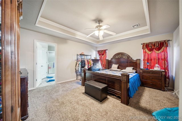 bedroom with carpet flooring, ceiling fan, a raised ceiling, and ensuite bath