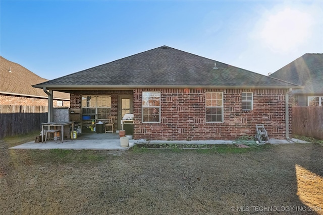 back of property with a lawn and a patio