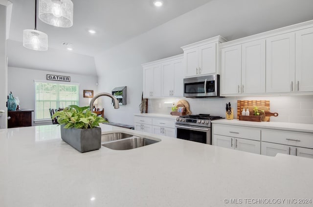 kitchen featuring sink, hanging light fixtures, decorative backsplash, appliances with stainless steel finishes, and white cabinetry