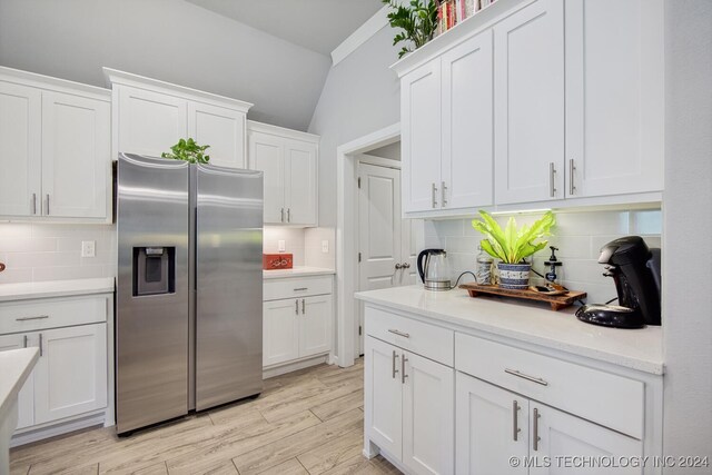 kitchen with white cabinets, stainless steel fridge with ice dispenser, backsplash, and light hardwood / wood-style flooring