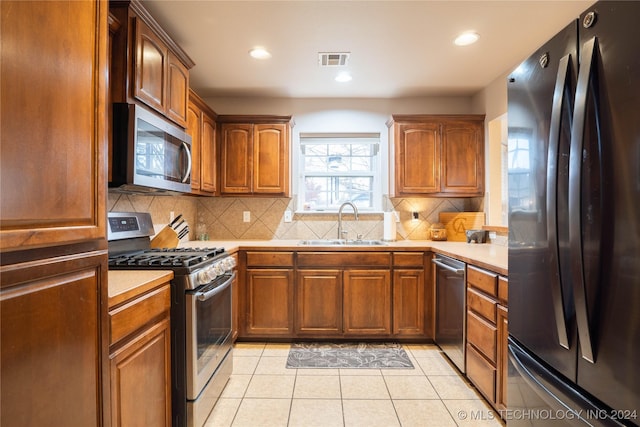 kitchen with backsplash, sink, light tile patterned floors, and stainless steel appliances