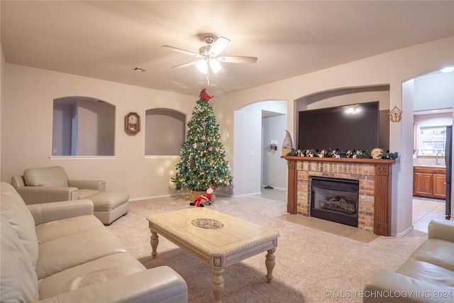 living room featuring a fireplace, light colored carpet, and ceiling fan