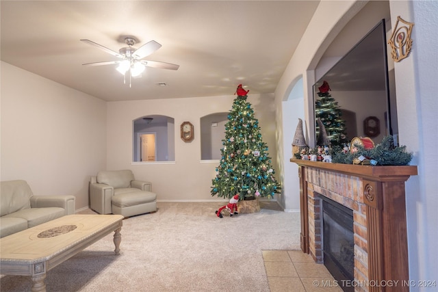 carpeted living room featuring a tile fireplace and ceiling fan