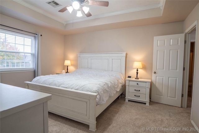 bedroom featuring a tray ceiling, ceiling fan, crown molding, and light carpet