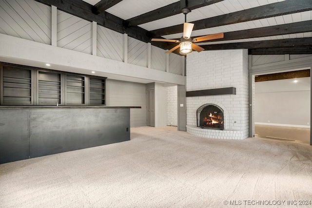 unfurnished living room with beam ceiling, ceiling fan, a brick fireplace, high vaulted ceiling, and carpet floors