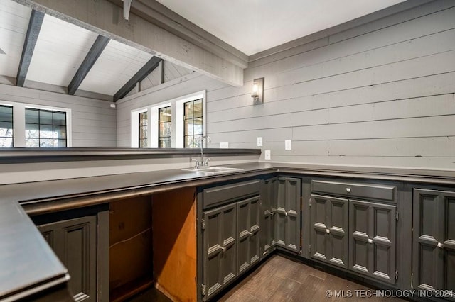 bar featuring dark hardwood / wood-style flooring, lofted ceiling with beams, wood walls, and sink