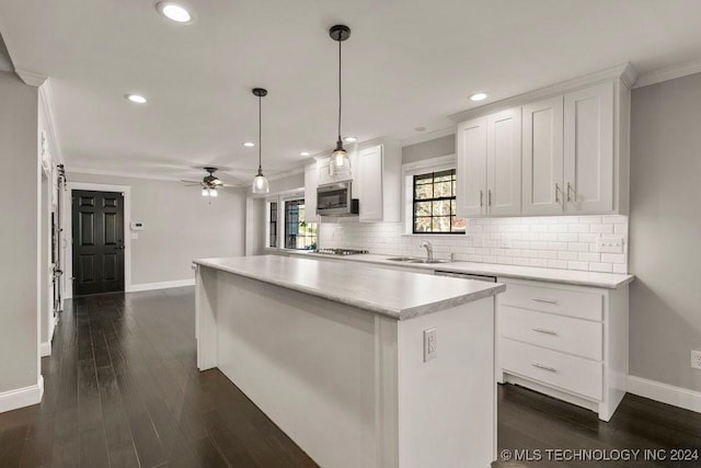 kitchen with white cabinets, a kitchen island, appliances with stainless steel finishes, hanging light fixtures, and light countertops