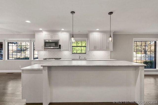 kitchen with appliances with stainless steel finishes, white cabinets, and decorative light fixtures