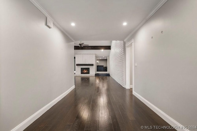 unfurnished living room featuring ceiling fan, dark wood-type flooring, baseboards, ornamental molding, and a brick fireplace