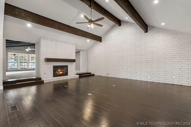 unfurnished living room with a brick fireplace, hardwood / wood-style flooring, vaulted ceiling with beams, ceiling fan, and brick wall